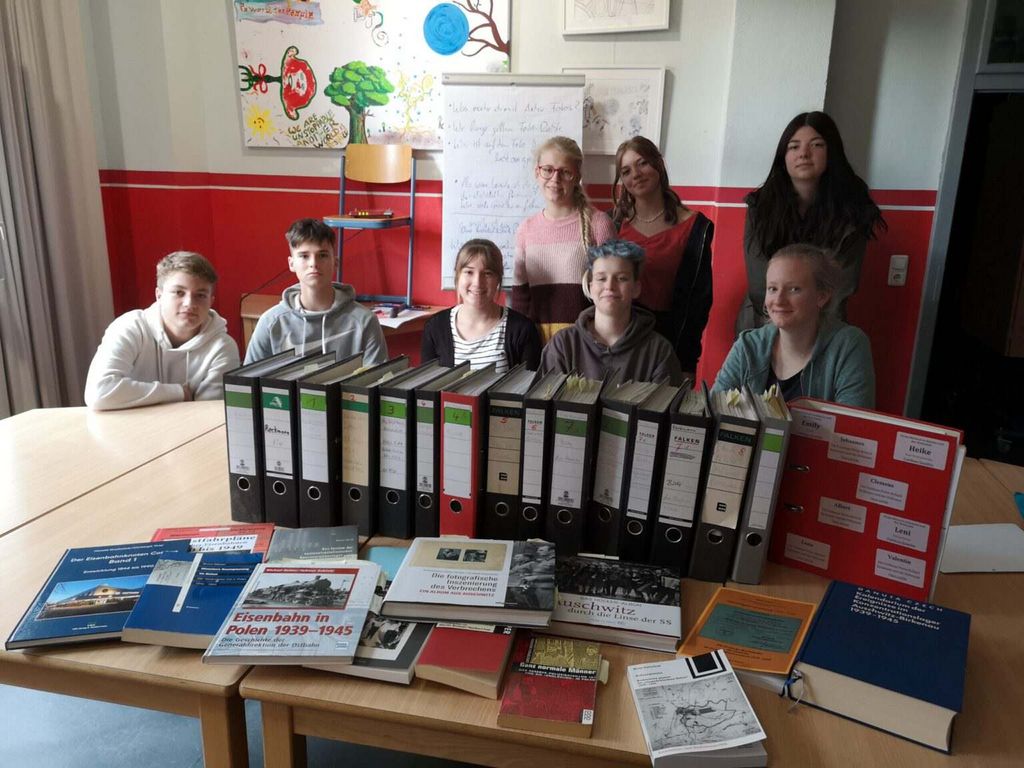Das Bild zeigt Schülerinnen und Schüler des Max-Steenbeck-Gymnasiums Cottbus, die eine Ausstellung Ausstellung über die Cottbuser Gleisbaufirma Reckmann erarbeiten. Im Vordergrund sidn zahlreiche Aktenordner und Bücher zu sehen. 